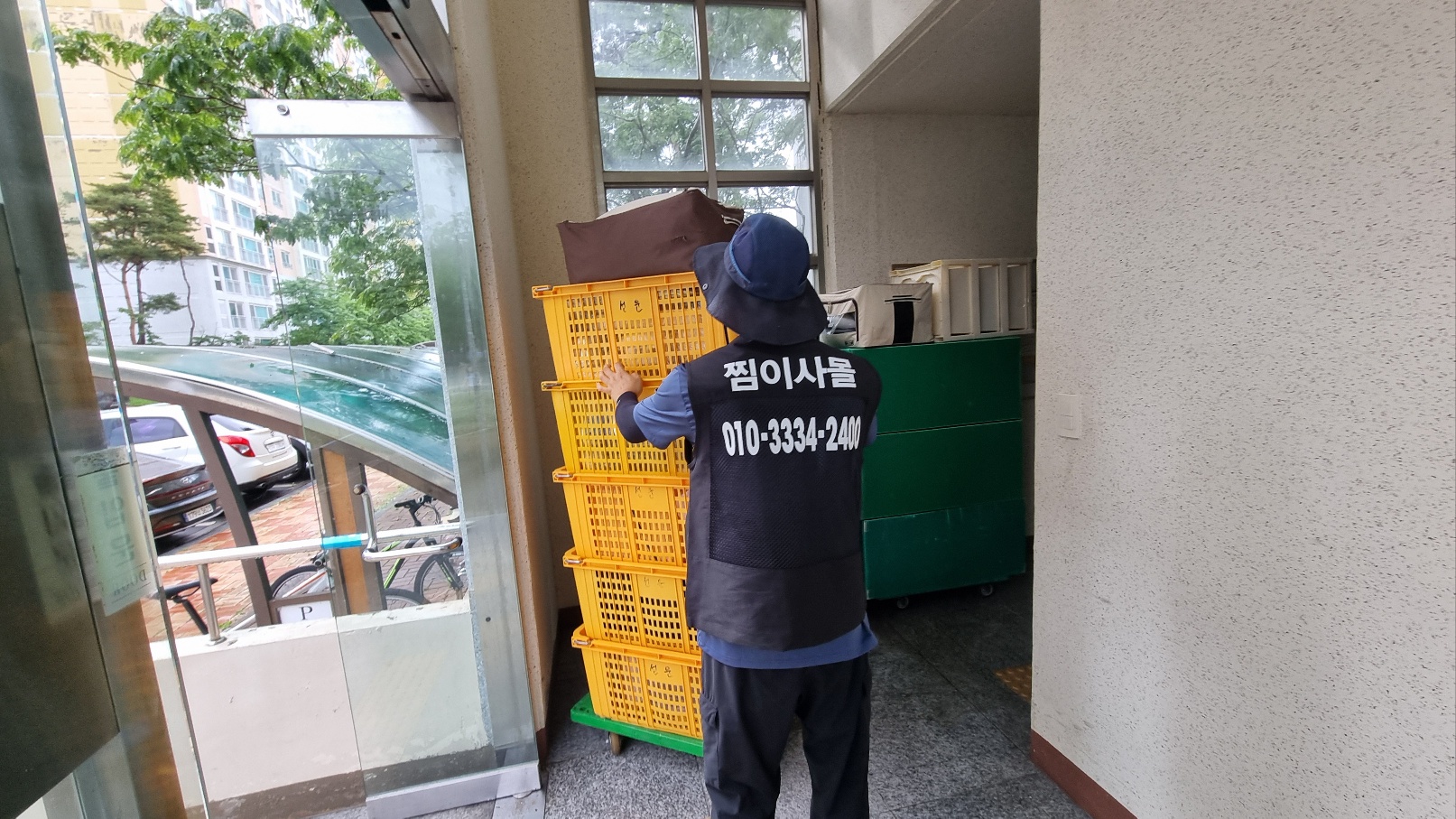 찜이사몰 작업자가 노란 이사 바구니를 대차로 운반하는 모습