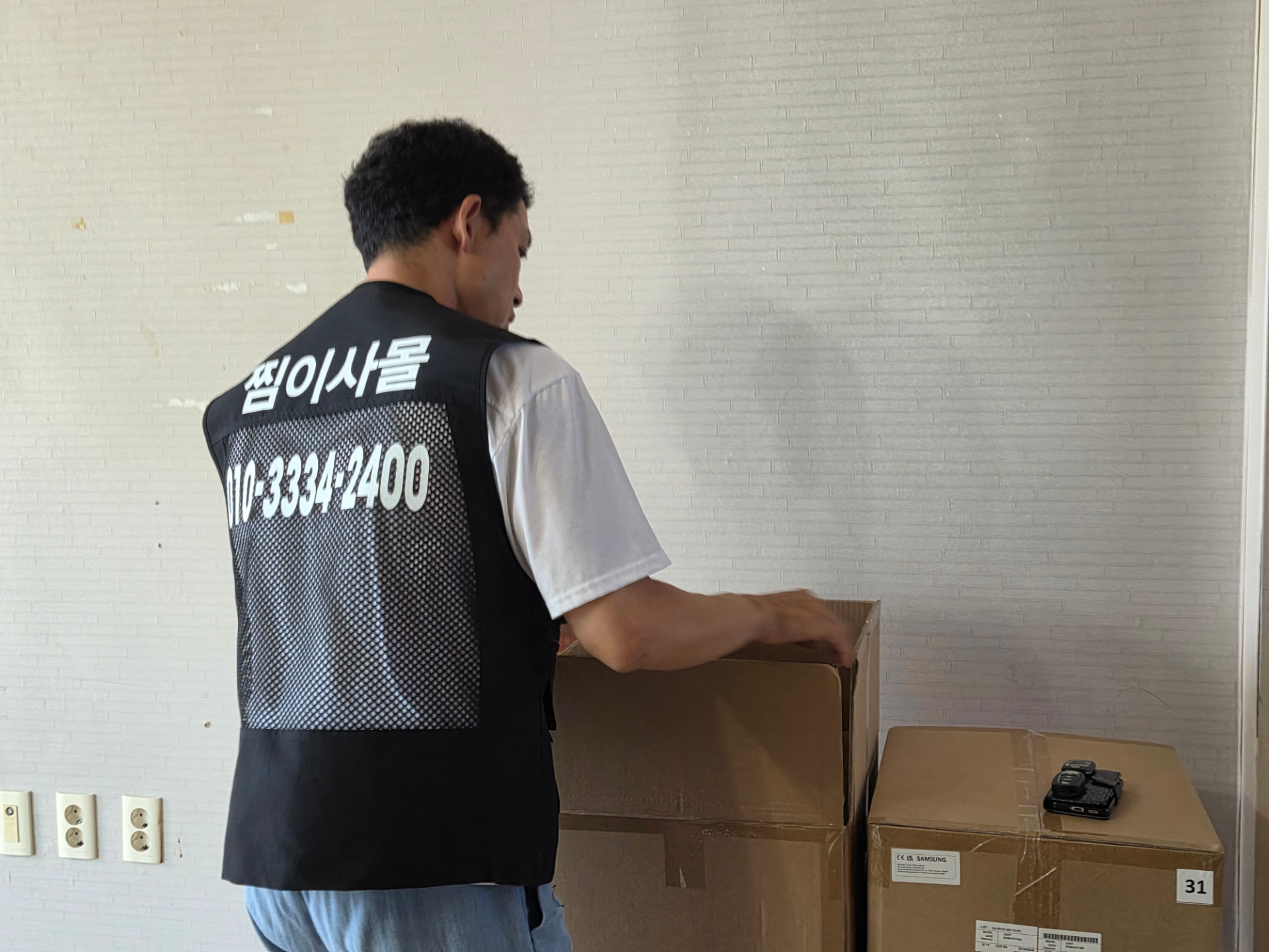 찜이사몰 작업자가 대형 가전 박스를 옮기는 모습