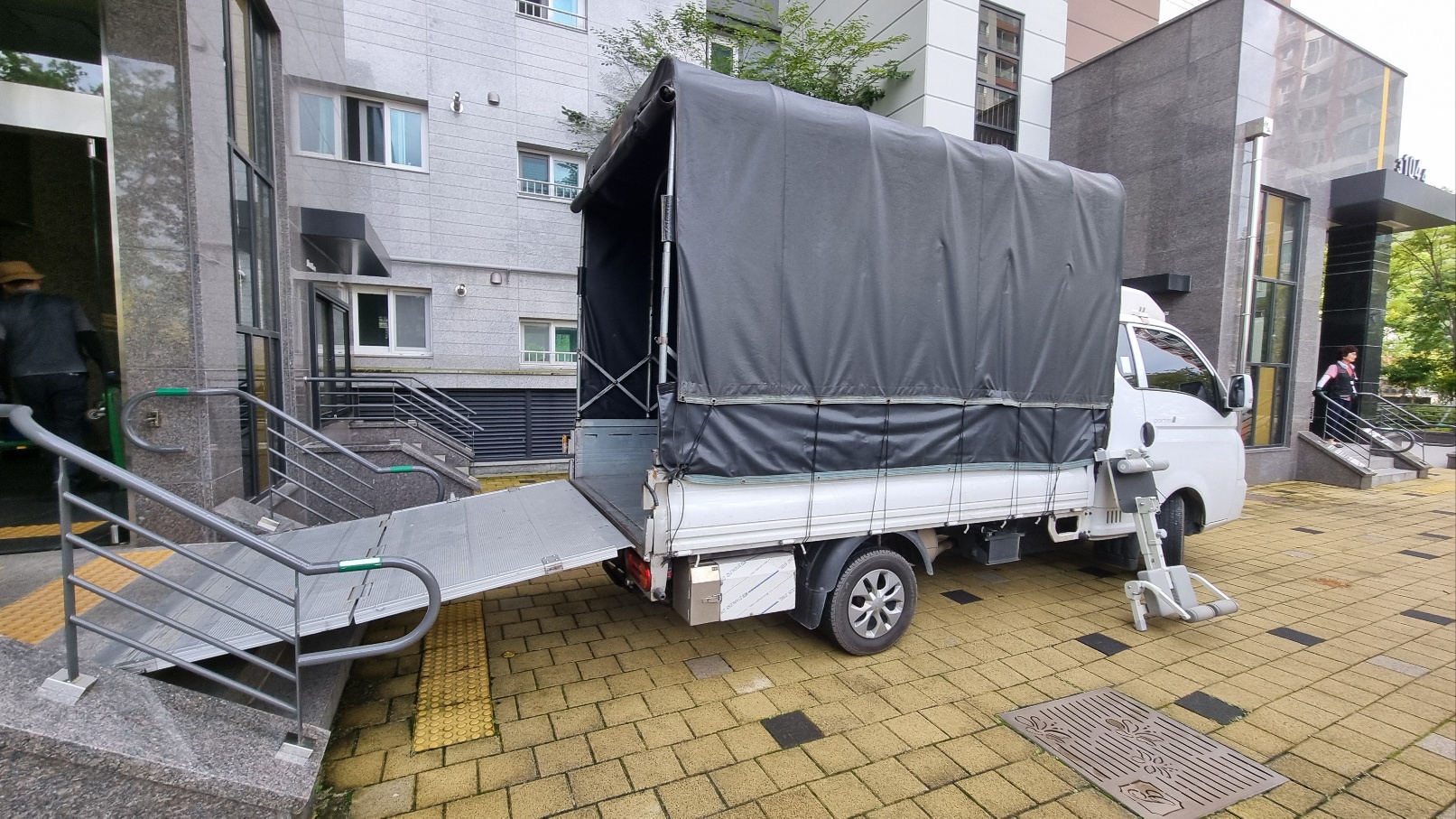 아파트 입구에서 리프트를 내린 1톤 이사 트럭