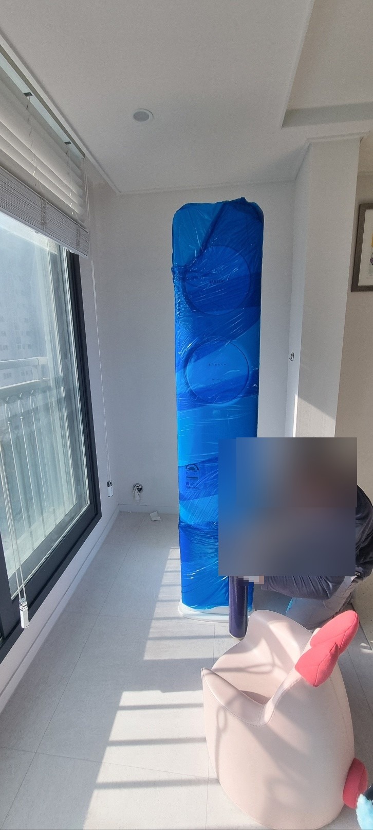 스탠드 에어컨을 비닐과 완충재로 안전하게 포장하는 작업자